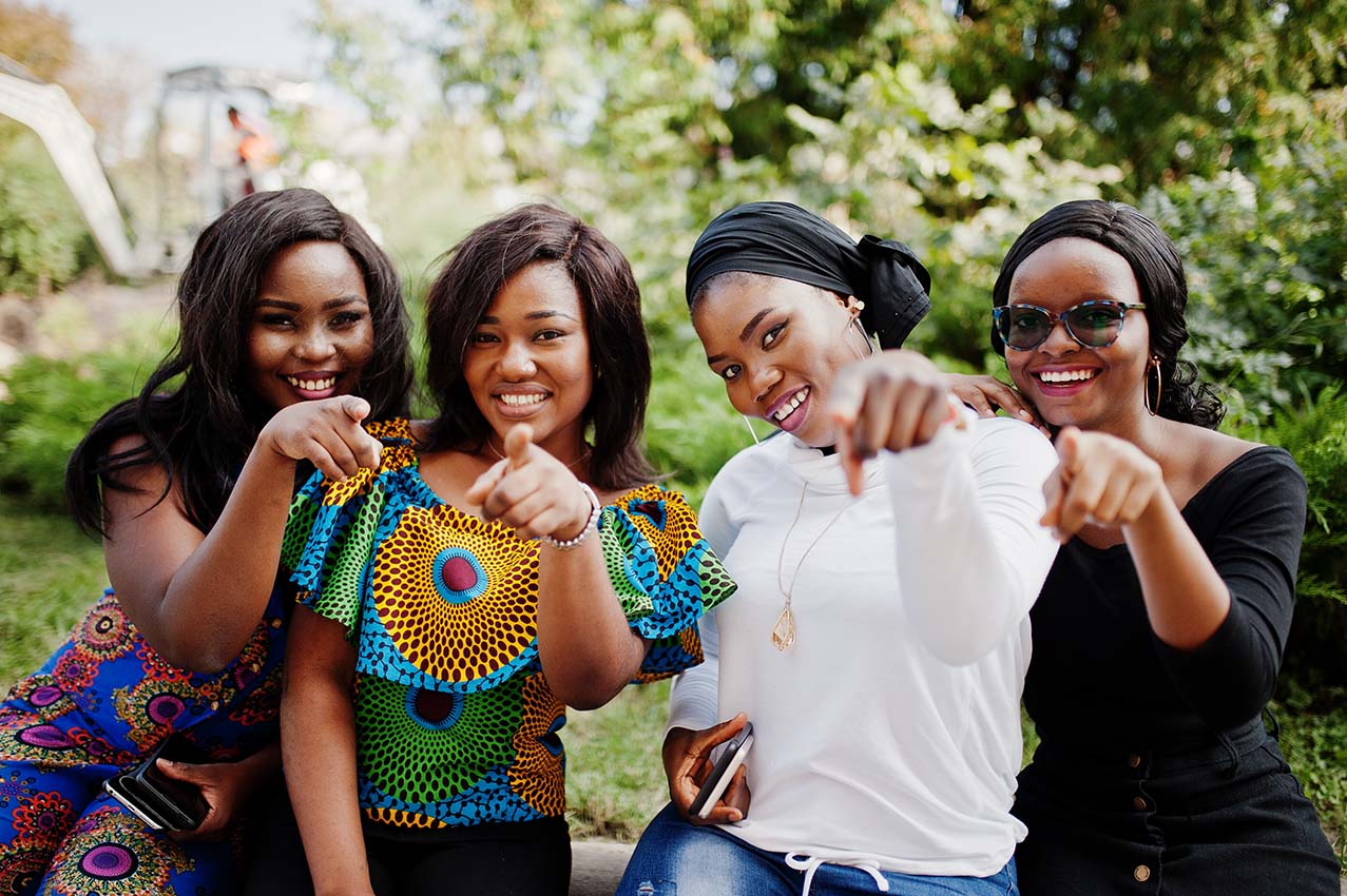 Group of four african american girls sitting outdoor and showing